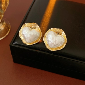 Vue macro de boucles d'oreilles cœur en or 16K avec texture en résine baroque