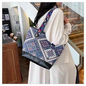 Detailed shot of ethnic geometric pattern canvas tote bag with black leather base and wide strap