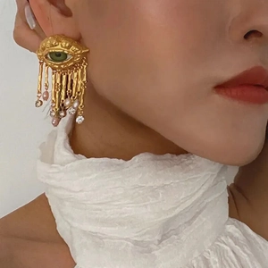 Bohemian gold Evil Eye earrings with green center and pink pearl tassels on model