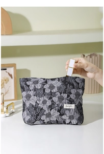 Vue détaillée d'une trousse à maquillage en jacquard fleuri avec étiquette tissée