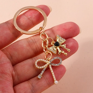 Elegant gold metal keychain with black heart gem and pearl rhinestone bow charm