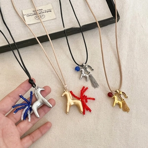 Detailed close-up of handmade horse pendants with beaded tassels and velvet cords