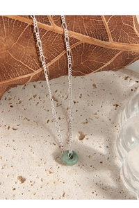 Detail shot of a minimalist S925 silver necklace with a green jade ring pendant on stone