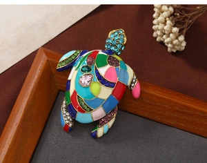 Artistic turtle brooch with colorful rhinestones and enamel on a vintage background