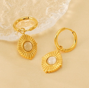 Détail de boucles d'oreilles vintage avec pierre œil de chat et pendentif soleil doré