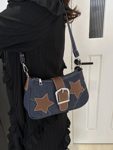 Detail of blue denim hobo bag featuring brown leather stars and silver buckle closure