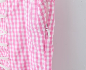 Close-up of pink plaid top showing the invisible side zipper and lacing detail