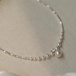 Elegant pearl necklace with silver chain and zircon diamond pendant on beige fabric