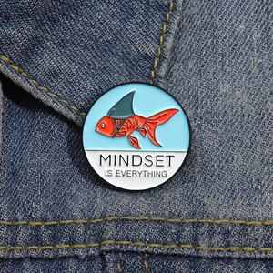 Enamel koi fish pin with mindset is everything text on dark denim fabric background