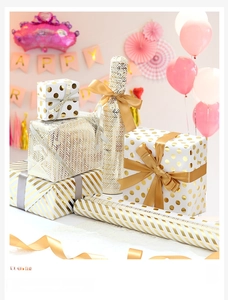 Close-up of white and gold geometric gift wrap rolls with elegant silk ribbons