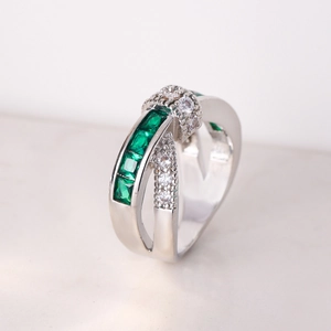 Macro view of silver cross ring with square green stones and pave diamond accents