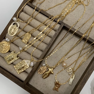 Gold pendant necklace set featuring Virgin Mary icon and pearls in a jewelry display box