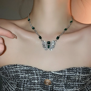 Vue détaillée du collier papillon de luxe avec émeraudes vertes sur le cou du modèle