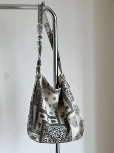 Detail of bohemian paisley canvas tote bag with black and white prints on a metal stand