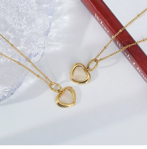 Detail of a gold heart pendant necklace with mother of pearl inlay on a red book base