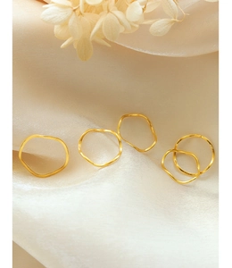 Set van vijf golvende gouden ringen op elegante beige zijden stof met gedroogde bloemen
