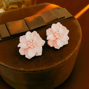 Gros plan de boucles d'oreilles fleurs roses avec perles dans une boîte cadeau