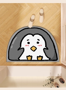 Detail showing the absorbent penguin bath mat texture on a natural wooden floor surface
