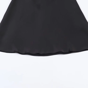 Detail shot of black satin dress hemline showing smooth texture and premium stitching