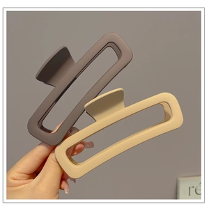 Detail view of large matte rectangular shark clips in brown and beige colors