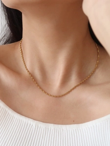 Minimalist sparkling gold stainless steel wave chain necklace worn on model's neck