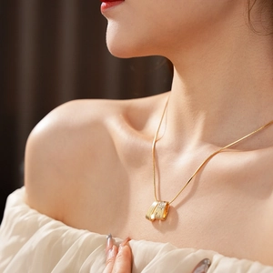 Close-up of golden brushed texture rectangular pendant with zircons on a snake chain