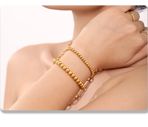 Detail of 4mm gold beaded stainless steel bracelets stacked on a wrist in close-up view