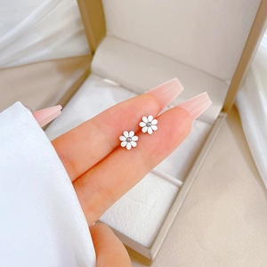 Minimalist daisy earrings in titanium steel held by hand to show 1cm product scale