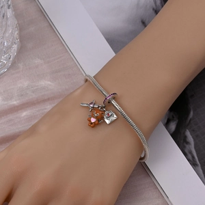 Detailed shot of silver snake chain bracelet with Peace envelope and brown bear charms