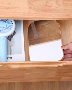 Placing a portable rabbit-ear vanity mirror into a wooden drawer for easy storage