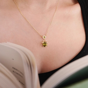 Detail of 18K gold plated necklace with an oval emerald green zircon pendant on model neck