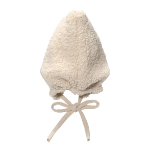 Close-up of fluffy cream lamb wool earflap hat with tie-up bow for winter warmth