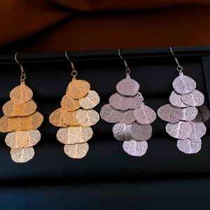 Detail of bohemian leaf cutout drop earrings in gold and silver on a jewelry display