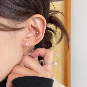 Detail of minimalist silver zircon stud and beaded pearl ring on a fashion model