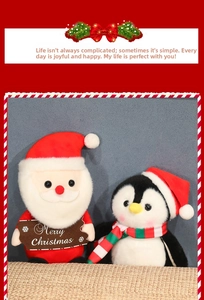 Dettaglio di peluche Babbo Natale e pinguino con cartello Merry Christmas e sciarpa a righe