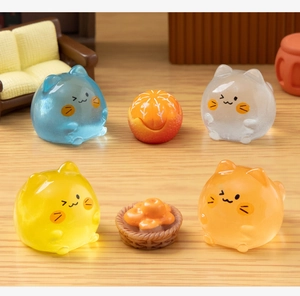 Close-up of mini luminous cat figurines and fruit models on a miniature wooden table