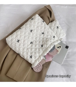 Detailed view of quilted white polyester handbags with black bow prints showing large capacity