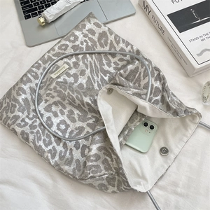 Detail of silver leopard print tote bag featuring a magnetic clasp and internal phone pocket