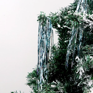 Silver and blue gradient tinsel fringe curtain hanging on snowy Christmas tree branches