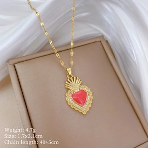 Detail view of gold heart necklace with red stone and crown on a jewelry box