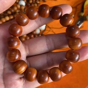 Close-up of polished red cedar barrel beads showing natural wood grain and texture