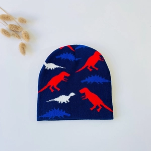 Close-up of baby knitted beanie with colorful dinosaur patterns on navy blue fabric