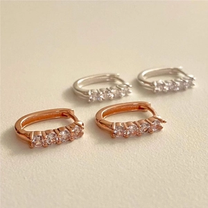 Macro shot of silver and rose gold huggie hoop earrings with sparkling zircon row settings