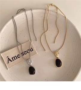 Detail of adjustable gold and silver snake chains with oval black resin pendants