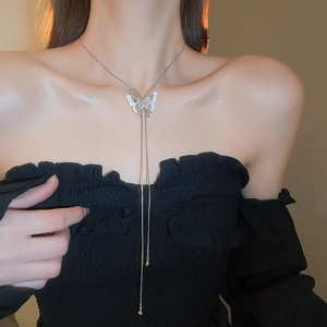 Detail shot of a butterfly pendant necklace with long dangling snake chain tassels