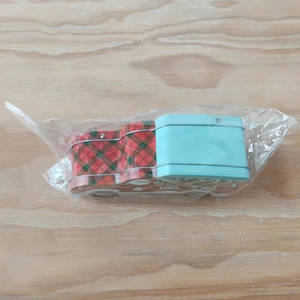 Close-up of red plaid Christmas tin candy box car in plastic protective packaging