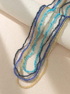 Detailed close-up of Bohemian colorful seed bead waist chains on a cylindrical stand
