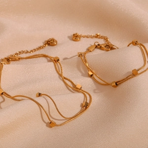 Detail of 18K gold plated double layer snake chain anklet with cube beads on silk
