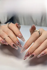 Detail of long ballerina nails with black dragon prints and silver cross charms