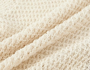 Detailed macro view of cream knit fabric texture on women's polo cardigan and shorts set